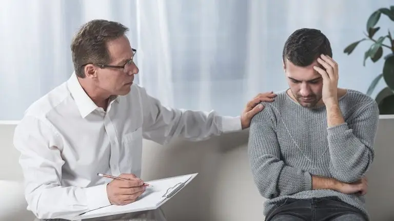 A man with a clipboard consoling a stressed looking man.