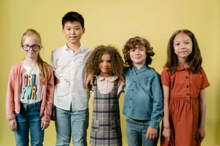 A group of diverse children stand together against a yellow backdrop